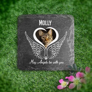 May include: A black slate pet memorial with a white heart and angel wings design. The heart has a photo of a tabby cat inside. The text "MOLLY" and "May Angels be with you" are printed in white on the slate.
