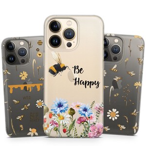 Könnte beinhalten: Drei transparente Handyhüllen mit einem floralen und Bienen-Design. Die mittlere Hülle hat eine Biene und den Text "Be Happy". Die linke Hülle hat eine Biene und den Text "Wild Bee Honey". Die rechte Hülle hat eine Biene und ein Blumenmuster.