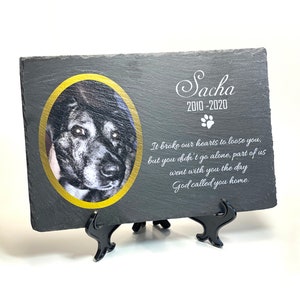 May include: Black slate memorial plaque with a gold-rimmed photo of a dog and the text "Sacha 2010-2020" and a paw print. The plaque also includes the text "It broke our hearts to loose you, but you didn't go alone, part of us went with you the day God called you home."