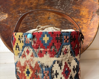 Vintage kilim bag, leather bucket bag with shoulder straps. Tobacco pouch closure with decorative beads. Measures 20x17 cm