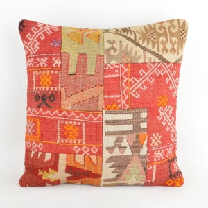 Könnte beinhalten: Quadratisches Zierkissen mit Patchwork-Design. Das Kissen weist eine Vielzahl geometrischer Muster in Rot-, Orange-, Beige- und Brauntönen auf. Das Kissen ist etwa 45 cm groß.