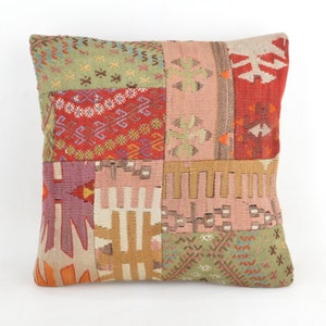 Puede incluir: Cojín cuadrado de patchwork con una variedad de colores y patrones. El cojín presenta una mezcla de parches rojos, verdes, rosas y beige con diseños geométricos y florales. Es un artículo decorativo.