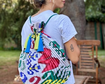 Pleated bag in a Japanese design and style with ikat fabrics. It measures 50x55 cm with a satin lining, cords with crystal beads and pompoms.