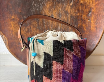 Vintage kilim bag, leather bucket bag with shoulder straps. Tobacco pouch closure with decorative beads. Measures 20x17 cm
