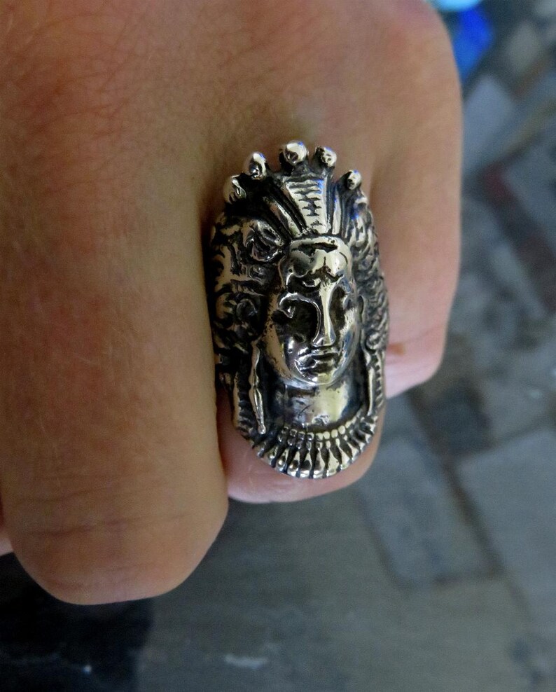 Peut inclure: Une bague en argent avec un design d&eacute;taill&eacute; d'un visage de femme portant une couronne. La bague est port&eacute;e sur un doigt.