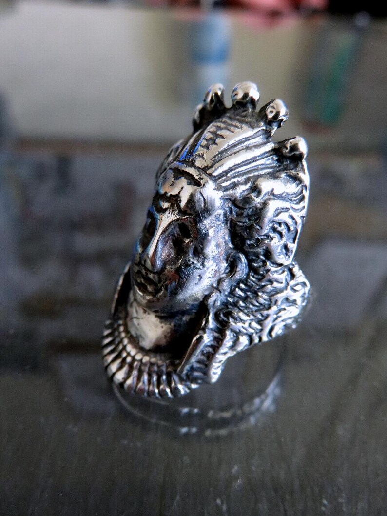Peut inclure: Une bague en argent avec un design d&eacute;taill&eacute; d'une t&ecirc;te de personne portant une couronne. La bague est en m&eacute;tal et a une surface textur&eacute;e.