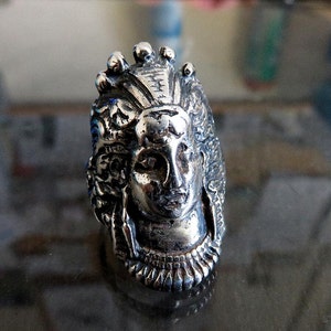 Peut inclure: Une bague en argent avec un design d&eacute;taill&eacute; d'un visage de femme avec une couronne. La bague est en m&eacute;tal et pr&eacute;sente un design d&eacute;taill&eacute;.