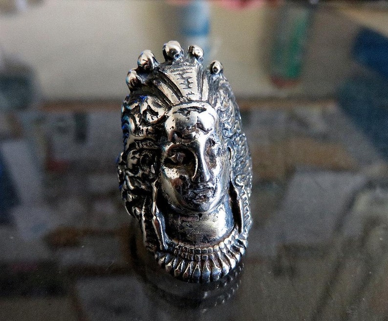 Peut inclure: Une bague en argent avec un design d&eacute;taill&eacute; d'un visage de femme avec une couronne. La bague est en m&eacute;tal et pr&eacute;sente un design d&eacute;taill&eacute;.