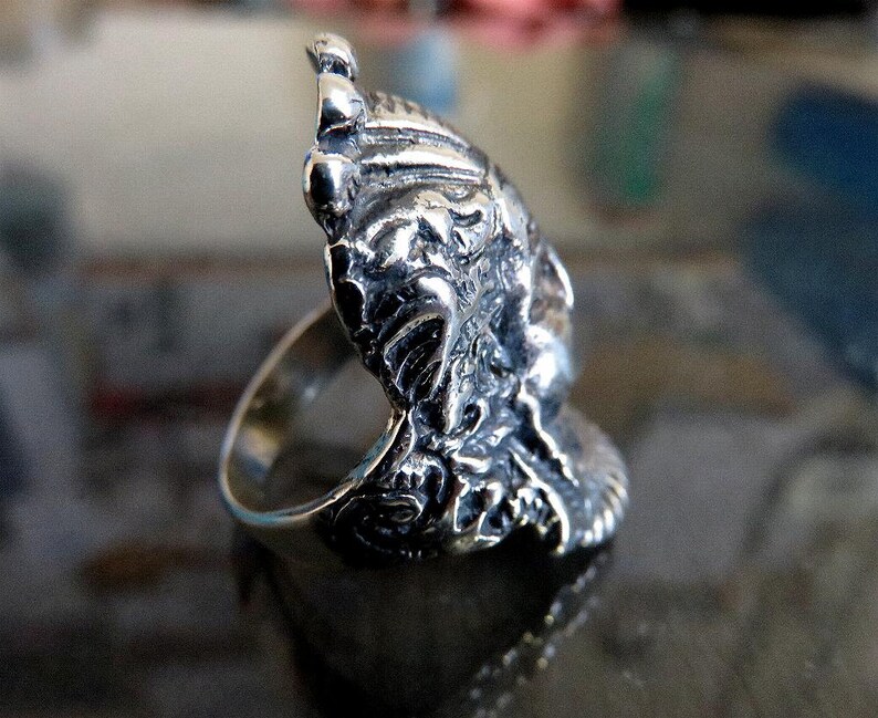 Peut inclure: Une bague en argent avec un design d&eacute;taill&eacute; et complexe d'un visage avec une couronne. La bague est en argent sterling et a une finition polie.