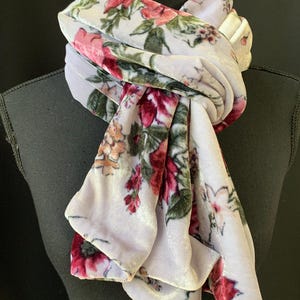 May include: A lavender velvet scarf with a floral print featuring pink, red, and green flowers.