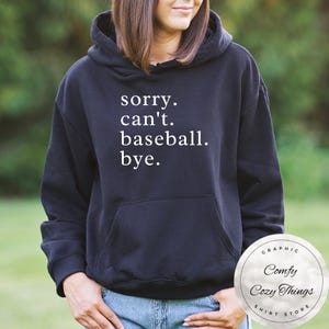 May include: Black hooded sweatshirt with white text that reads "sorry. can't. baseball. bye."