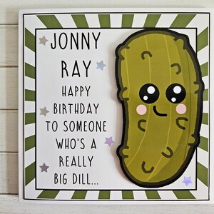 Peut inclure: Une carte blanche avec des rayures vertes et un cornichon de dessin anim&eacute; avec un visage souriant. La carte dit "Jonny Ray Joyeux anniversaire &agrave; quelqu'un qui est un tr&egrave;s gros cornichon..."