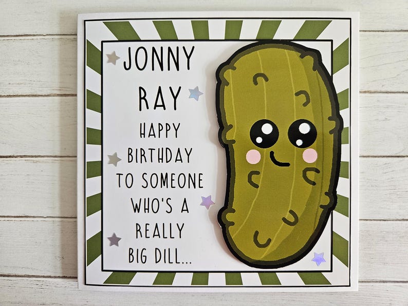Peut inclure: Une carte blanche avec des rayures vertes et un cornichon de dessin anim&eacute; avec un visage souriant. La carte dit "Jonny Ray Joyeux anniversaire &agrave; quelqu'un qui est un tr&egrave;s gros cornichon..."