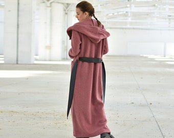 May include: A long, pink hooded coat with a black belt. The coat is made of a soft, fuzzy material and has a relaxed fit.
