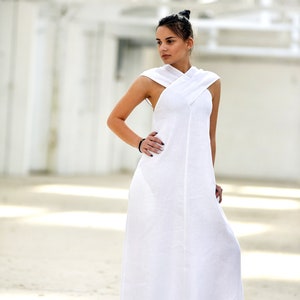 May include: A white linen maxi dress with a criss-cross halter neckline and a flowing silhouette.