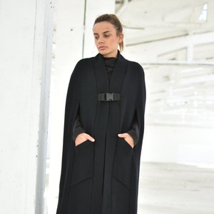 May include: A long black cape with a buckle closure and two pockets. The cape is made of a thick, warm fabric and is perfect for cold weather.