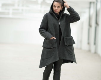 May include: A gray hooded coat with a zipper closure and large pockets. The coat is worn over black pants and black boots.