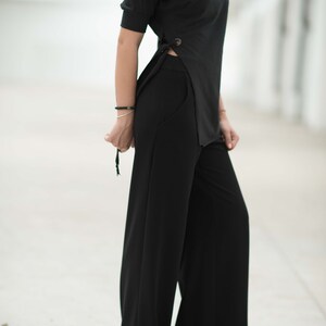 May include: A black mock neck top with a side slit and a pair of wide-leg black trousers.