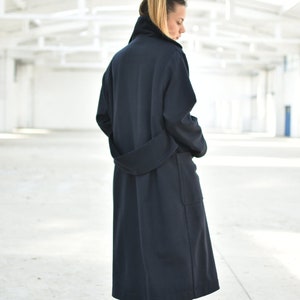 May include: A long, dark blue coat with a belt and pockets. The coat is made of a soft, comfortable fabric and has a relaxed fit.