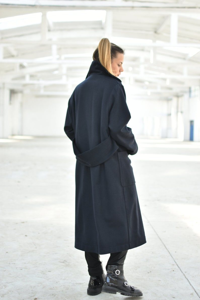 May include: A long, dark blue coat with a belt and pockets. The coat is made of a soft, comfortable fabric and has a relaxed fit.