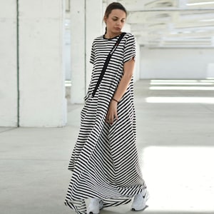 May include: A black and white striped maxi dress with short sleeves. The dress has a loose fit and a flowing silhouette.