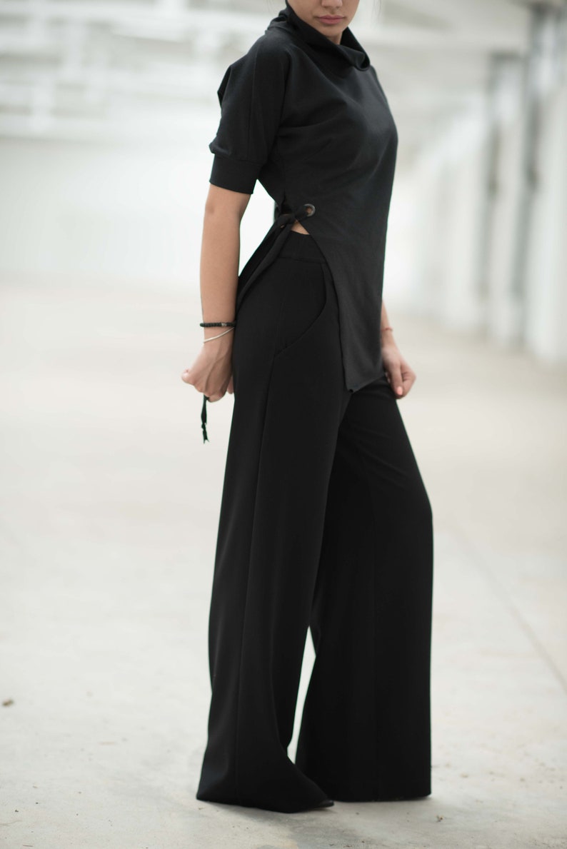 May include: A black mock neck top with a side slit and a pair of wide-leg black trousers.