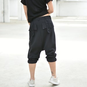 May include: Black, loose-fitting, cropped pants with large pockets on the back. The pants are made of a soft, comfortable fabric and have a relaxed fit.