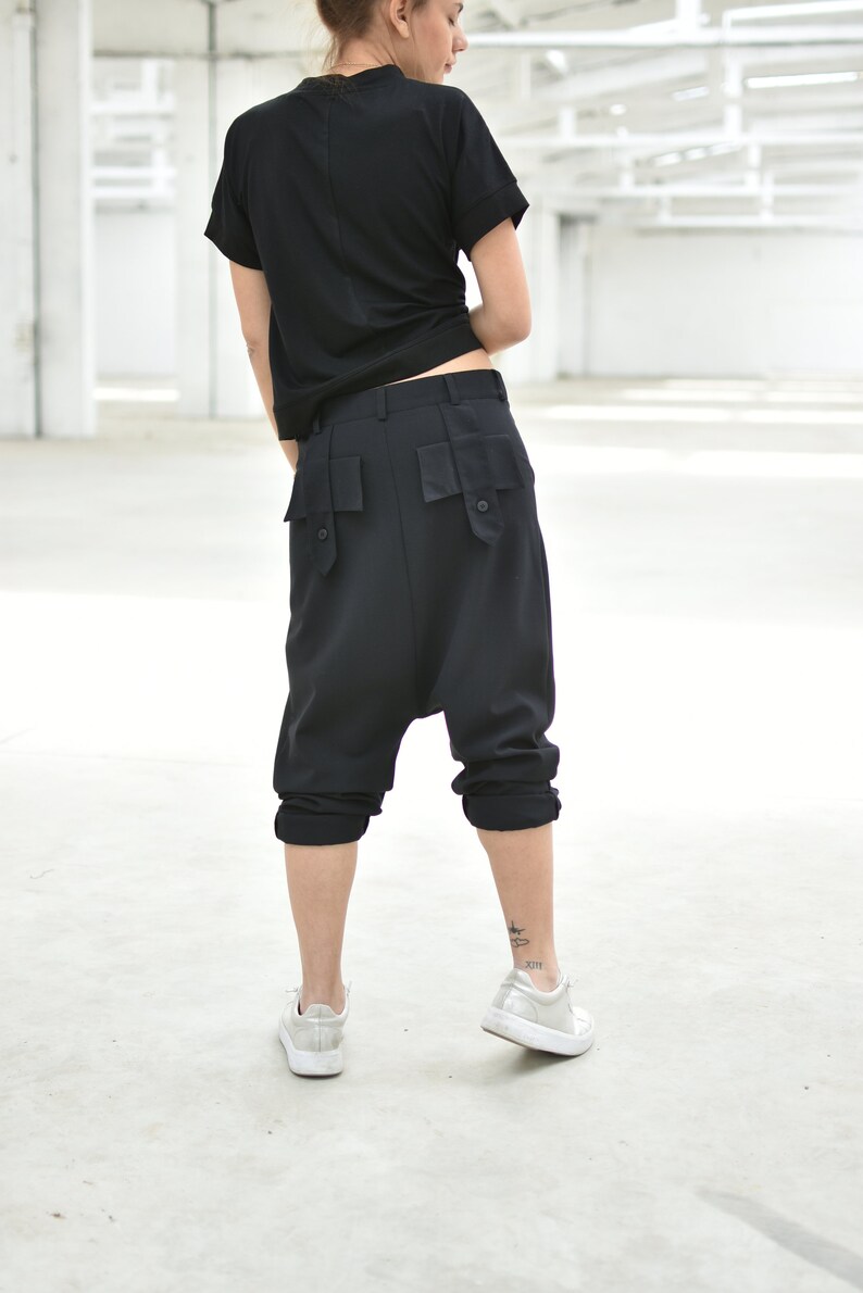 May include: Black, loose-fitting, cropped pants with large pockets on the back. The pants are made of a soft, comfortable fabric and have a relaxed fit.