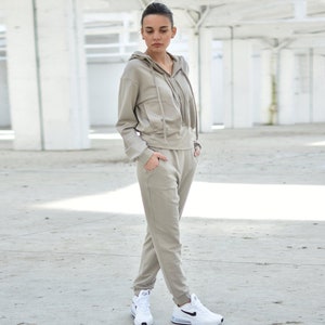 Puede incluir: Una sudadera con capucha de color marr&oacute;n claro y pantalones deportivos a juego. La sudadera tiene una cremallera y una capucha con cord&oacute;n. Los pantalones deportivos tienen un corte holgado y una cintura con cord&oacute;n.