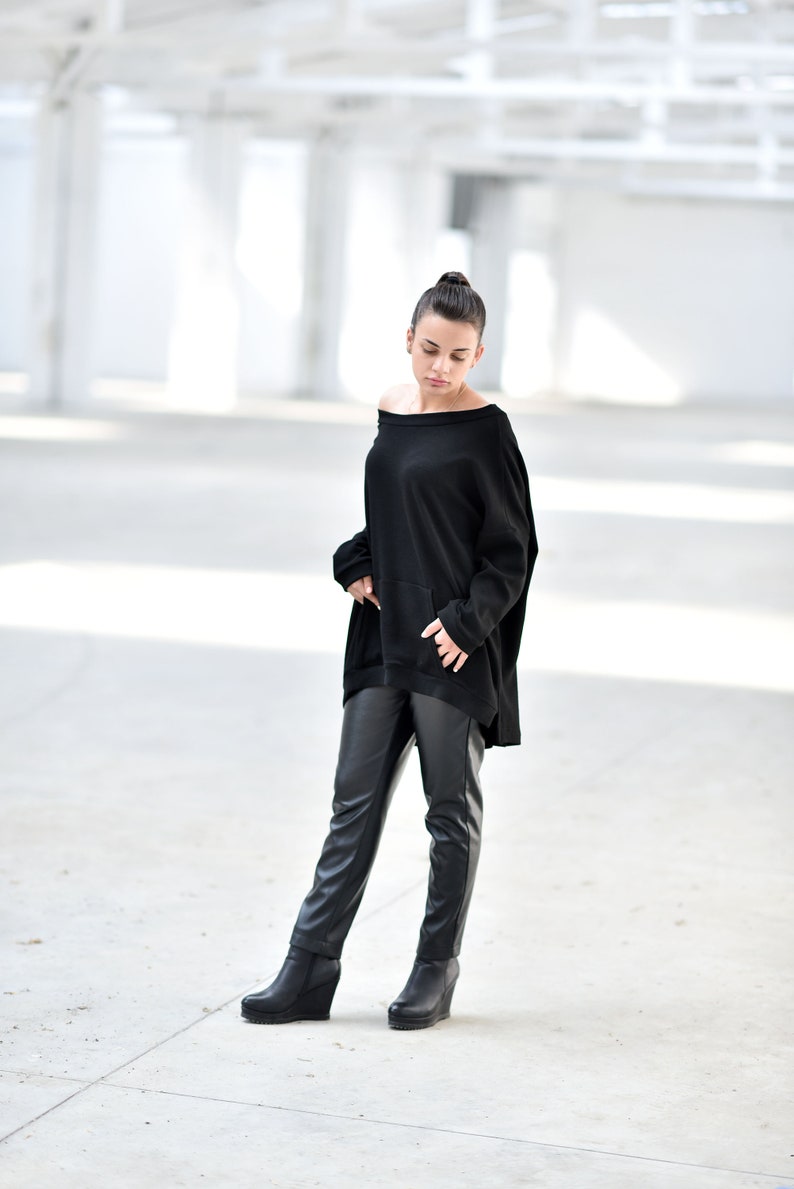 May include: A woman wearing a black off-the-shoulder sweater and black leather pants with a wedge heel boot.
