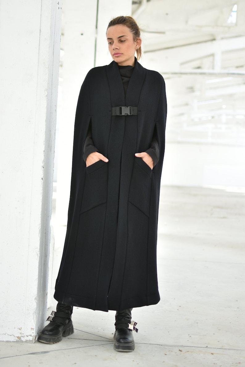 May include: A long black cape with a buckle closure and two pockets. The cape is made of a thick, warm fabric and is perfect for cold weather.