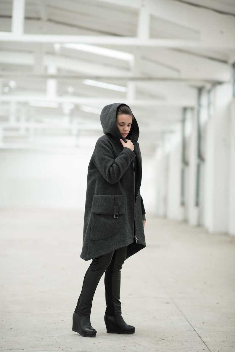 May include: A dark gray hooded coat with a zipper closure and a large pocket on the left side.