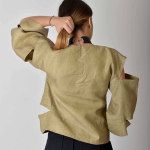 May include: A khaki linen blouse with cut-out details on the sleeves and a black choker necklace.