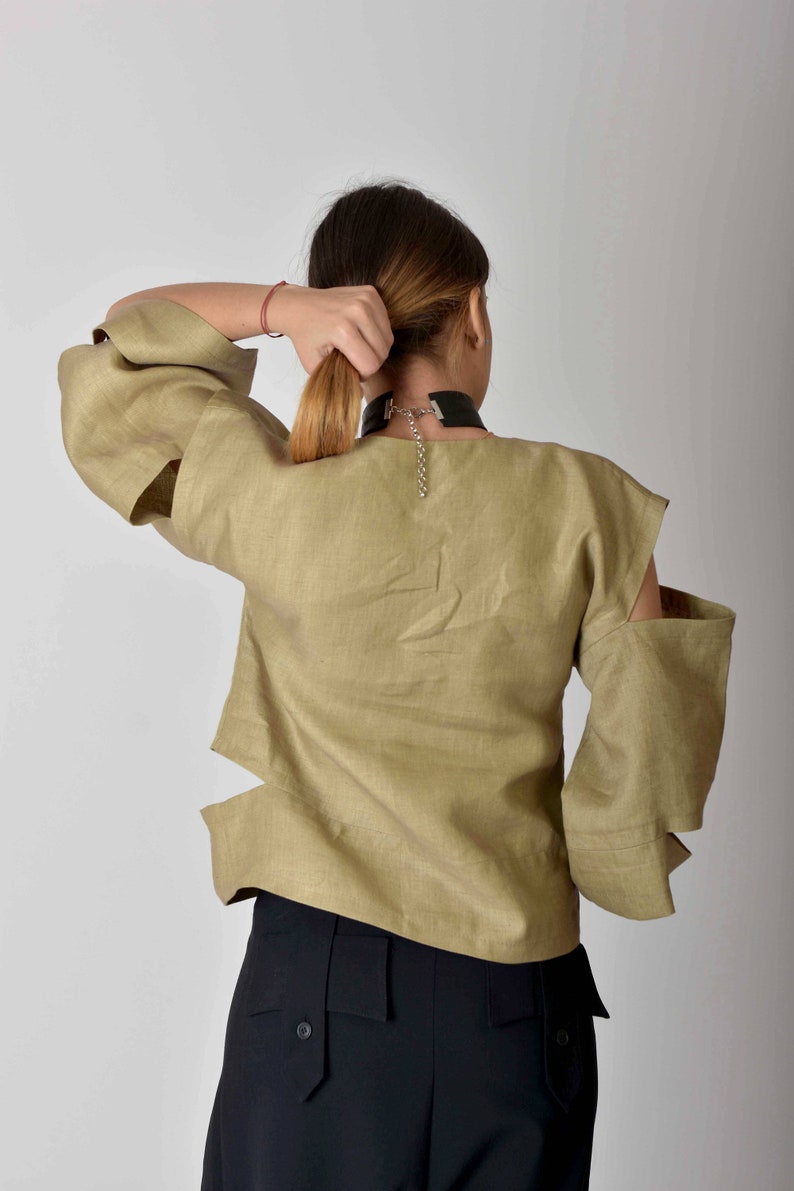 May include: A khaki linen blouse with cut-out details on the sleeves and a black choker necklace.