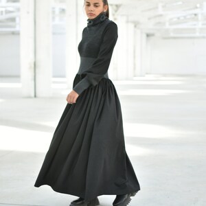 May include: A black long-sleeved dress with a high neck and a gathered skirt. The dress is made of a soft, comfortable fabric and has a relaxed fit.
