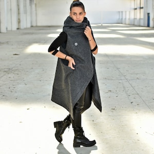 May include: A gray sleeveless coat with a high collar and a long, asymmetrical hem. The coat is made of a soft, textured fabric and has a relaxed fit.