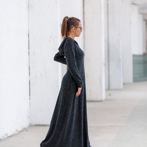 May include: A long, dark gray hooded dress with a flowing skirt. The dress is made of a soft, comfortable fabric and has a relaxed fit.