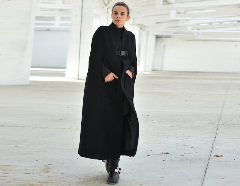 May include: A long black cape with a buckle closure. The cape is made of a soft, warm fabric and has a relaxed fit.