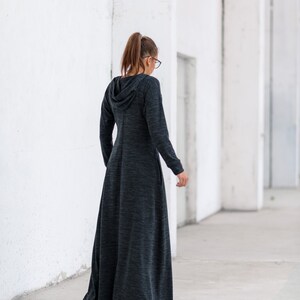 May include: A long, dark gray hooded dress with a loose fit and a flowing skirt. The dress is made of a soft, comfortable fabric.
