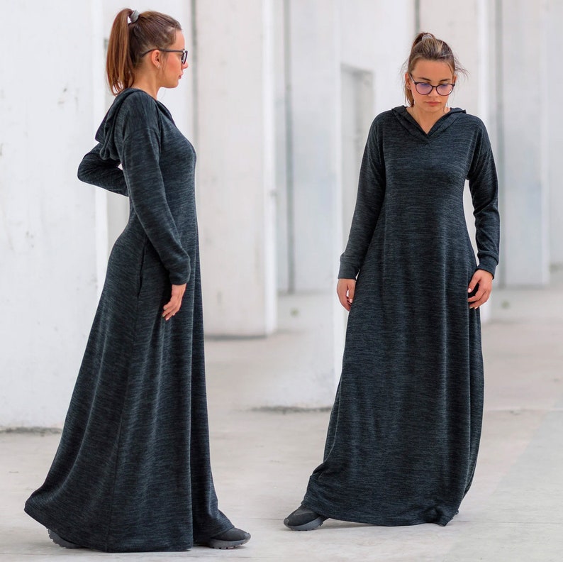 May include: Two women wearing long, dark gray hooded dresses with a marled texture. The dresses have a relaxed fit and flowy silhouette.