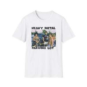 May include: White t-shirt featuring a black and white image of a group of people standing in front of a car. The text "Heavy Metal Parking Lot" is printed on the shirt.