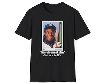 May include: Black t-shirt with a baseball card graphic of Ken Griffey Jr. in a blue cap and the text "My retirement plan - Every kid in the 90's-". The shirt has a crew neck.