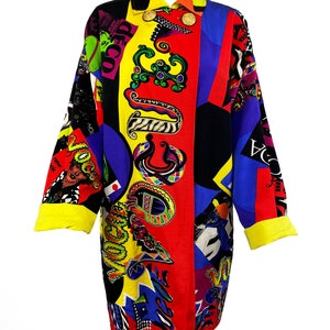 May include: A long-sleeved, colorful button-up shirt with a geometric pattern and the word "Vogue" repeated throughout. The shirt is made of a silky fabric and has a yellow collar and cuffs.