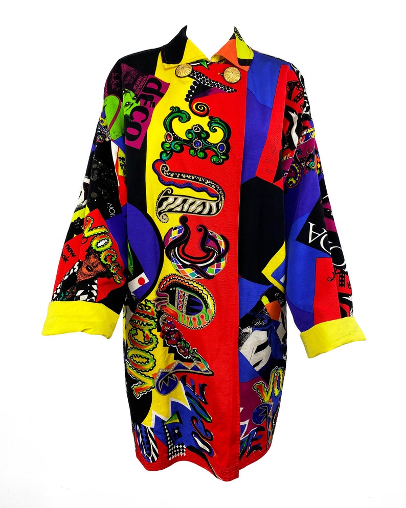 May include: A long-sleeved, colorful button-up shirt with a geometric pattern and the word "Vogue" repeated throughout. The shirt is made of a silky fabric and has a yellow collar and cuffs.