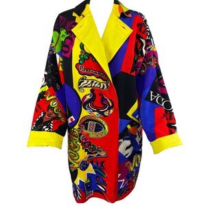 May include: A long-sleeved, multi-colored coat with a geometric pattern. The coat has a yellow collar and cuffs, and the pattern includes various colors, including red, blue, black, and yellow. The coat is made of a lightweight fabric and has a relaxed fit.