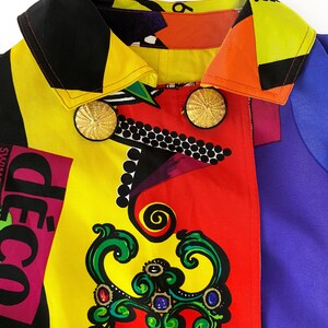 May include: A colorful jacket with a black collar and gold buttons. The jacket has a geometric pattern with red, yellow, blue, and black colors. The text "d&eacute;co" is visible on the jacket.