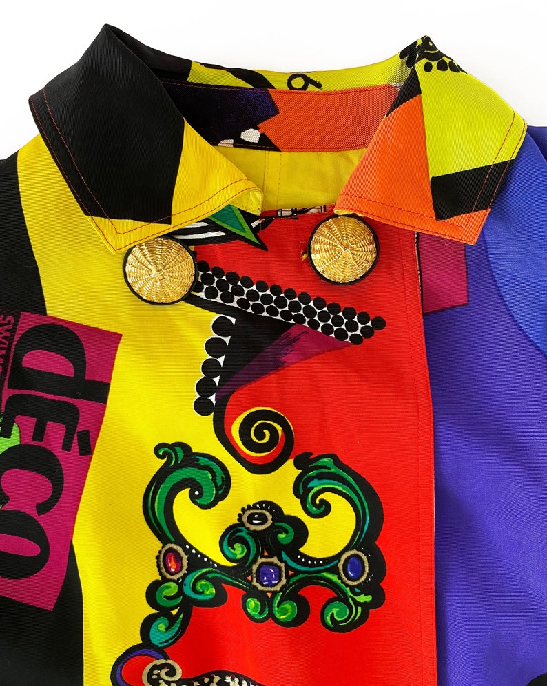 May include: A colorful jacket with a black collar and gold buttons. The jacket has a geometric pattern with red, yellow, blue, and black colors. The text "d&eacute;co" is visible on the jacket.