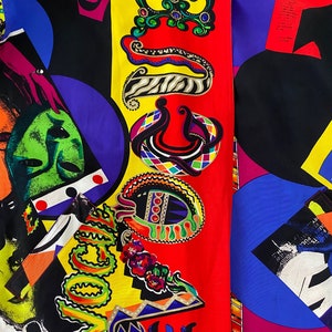 May include: A colorful fabric with a geometric pattern featuring a red, yellow, and blue color scheme. The fabric has a variety of shapes and designs, including circles, squares, and swirls. The fabric also features the word "Vogue" in a stylized font.