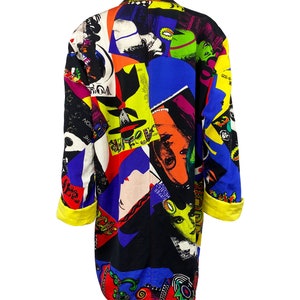 May include: A long black jacket with a colorful collage print featuring various images, including faces, text, and abstract designs. The jacket has yellow cuffs and a collar.