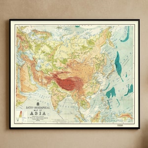 Peut inclure: Une carte bathy-orographique vintage encadrée de l'Asie. La carte présente une représentation détaillée du continent asiatique avec différentes couleurs représentant les différents terrains et altitudes. La carte est encadrée d'une bordure noire et est affichée sur un mur beige.
